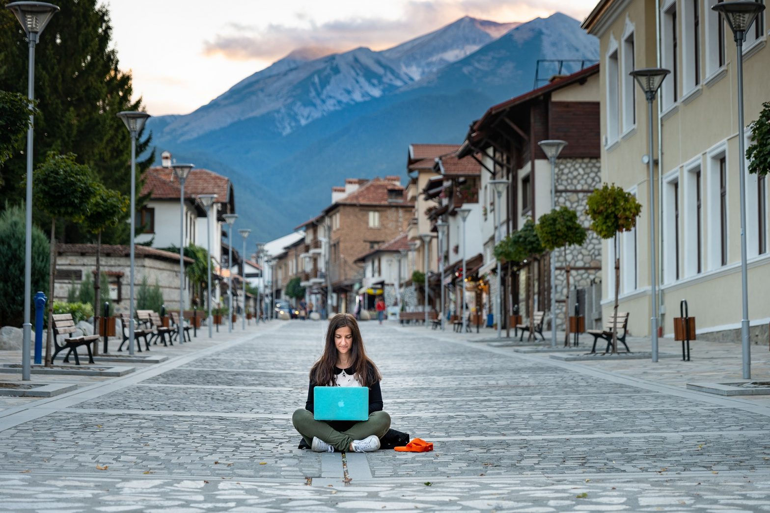 Mujer trabajando con un ordenador en la calle de un pueblo